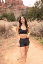 Woman in slate gray two-piece swimsuit designed to mimic athletic wear to take you from trail to board. 